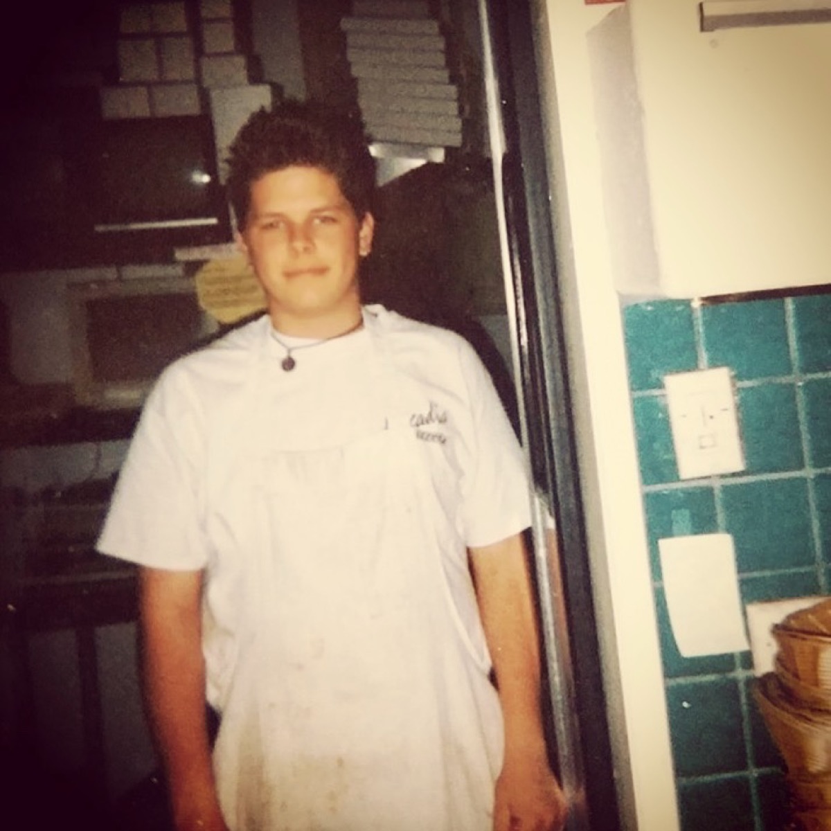 A young cook in stained kitchen whites in the doorway at Leucadia Pizzeria, Encinitas, late 1990s