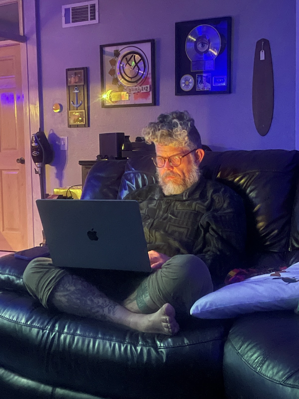 The proprietor working on a MacBook Pro late at night, seated on a couch at a client&rsquo;s home