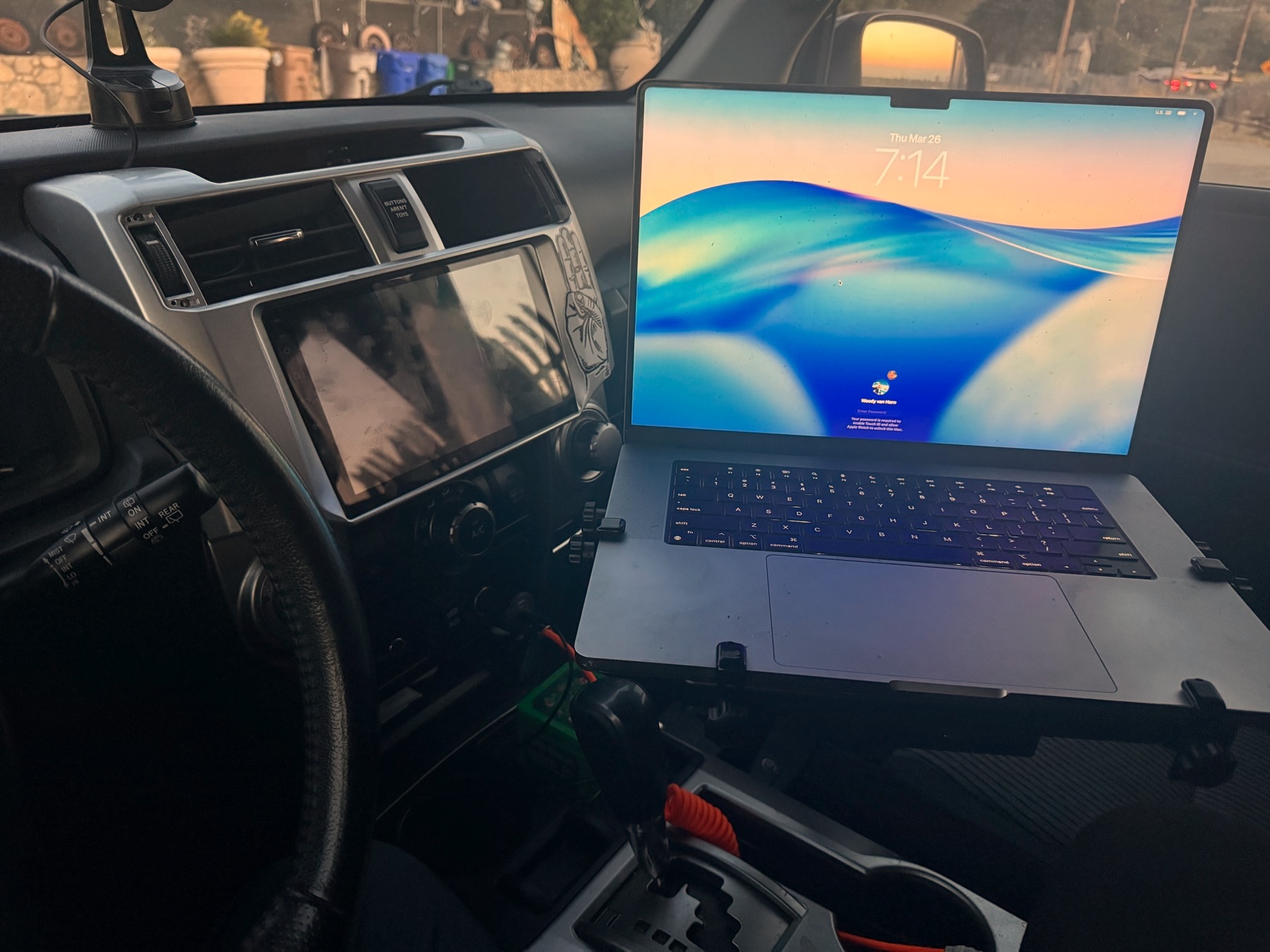 A 16-inch MacBook Pro mounted on a swing arm in the cab of a 4Runner at dawn
